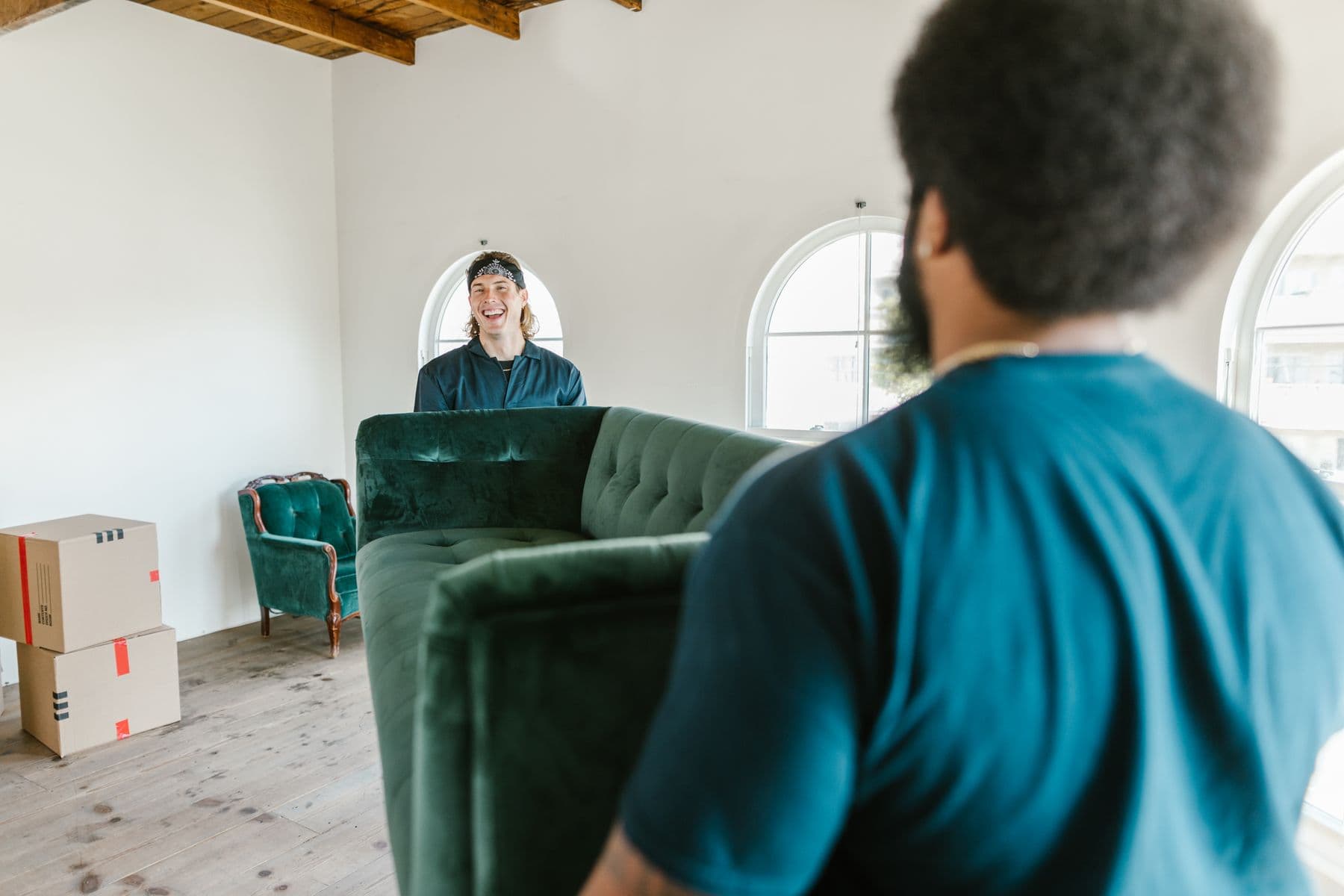 Two people carrying a large sofa through a room